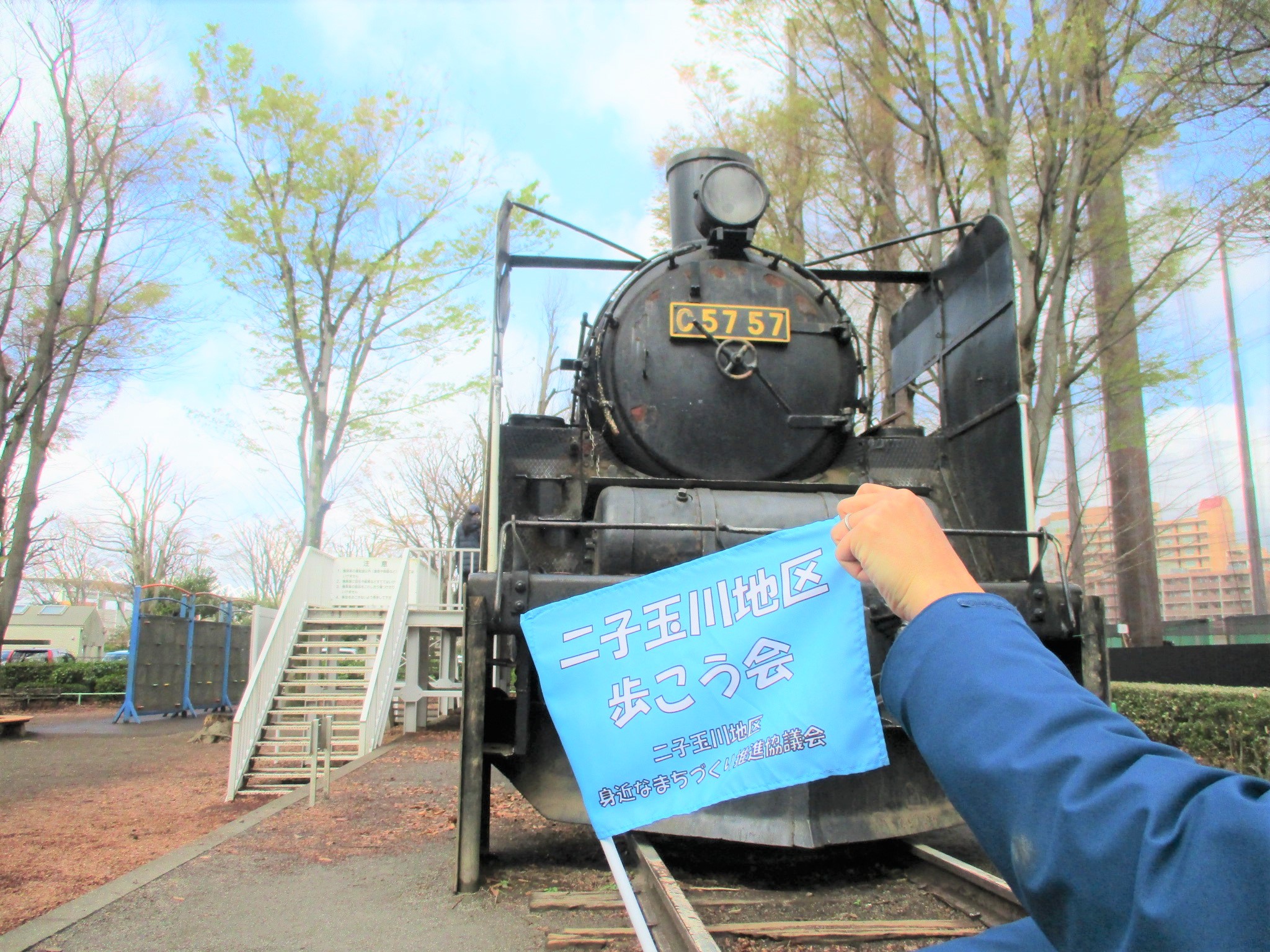 SLの前で春の歩こう会の旗を掲げている