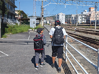 線路沿いを歩く親子の写真