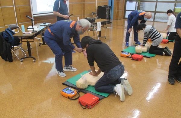 助言を受けながら人形で心肺蘇生の練習をする受講者
