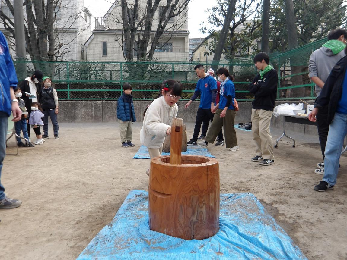 臼と杵を使ってもちつきの体験をする子ども